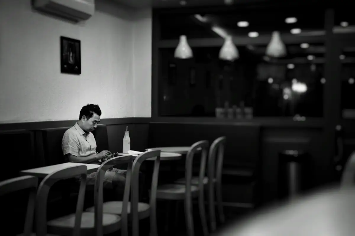 A man sitting alone with his phone in an empty room