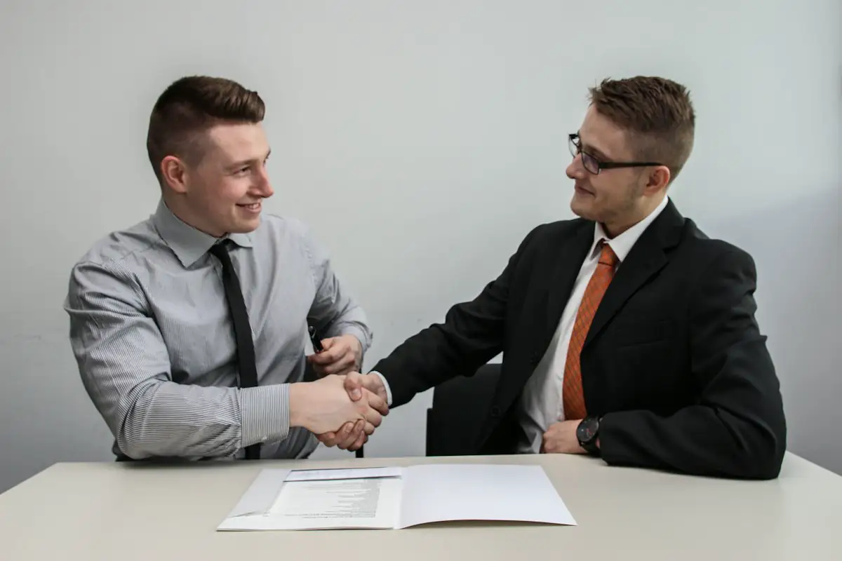Two people shaking hands and smiling after a meeting
