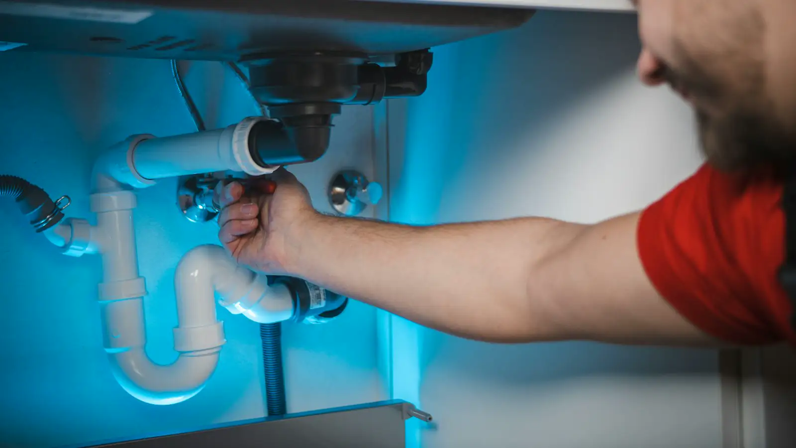 A plumber working on pipework inside a wall